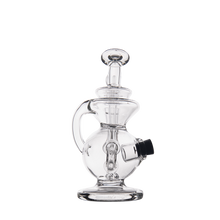 The MJ Arsenal Mini Jig Mini Dab Rig, featuring clear glass, a round base, side handle, vertical mouthpiece, and black bowl attachment, is shown against a plain white background.