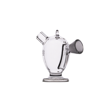The MJ Arsenal Dubbler Original Double Bubbler, made of clear borosilicate glass with a rounded body, flat base, handle, spout, and front cylinder for water filtration, is shown against a plain white background.