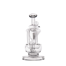 The MJ Arsenal Claude Mini Dab Rig, featuring a clear glass cylindrical base, curved neck, and detailed glasswork, is showcased against a plain white background.