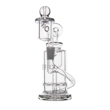 The MJ Arsenal Ursa Mini Dab Rig is a clear borosilicate glass water pipe with a cylindrical base, curved mouthpiece, and multiple internal tubes for filtration. It has a modern, intricate design and rests on a plain white background.