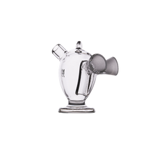 The MJ Arsenal Dubbler Original Double Bubbler is a clear borosilicate glass piece with a rounded body, dual angled openings, a side spout with gray cone-shaped filter attachment, and a flat base, shown on a white background.