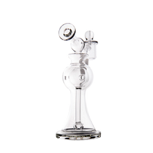The MJ Arsenal Apollo Mini Dab Rig is a clear borosilicate glass water pipe with a wide base, cylindrical neck, angled mouthpiece, intricate glasswork, and a side chamber designed for optimal flavor preservation.