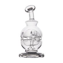 The MJ Arsenal Royale Vape Edition is a clear glass decanter with bold facial features and a tilted, round stopper, reminiscent of an abstract human face dab rig, displayed against a plain white background.