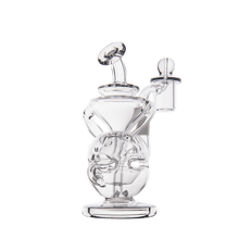 The MJ Arsenal Infinity Mini Dab Rig is a clear borosilicate glass piece featuring intricate twisting internal tubes, a side chamber, and a flat circular base, shown against a plain white background.