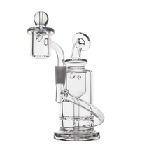 The MJ Arsenal Ursa Mini Dab Rig is a clear borosilicate glass piece featuring a cylindrical body, angled downstem, round base, and domed quartz banger attachment, displayed against a plain white background.