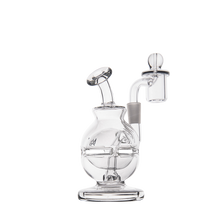 The MJ Arsenal Royale Mini Dab Rig is a clear borosilicate glass piece with a round base, angled mouthpiece, fab egg percolator, and attached quartz banger, shown on a plain white background.