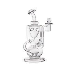 The MJ Arsenal Titan Mini Dab Rig, made of clear borosilicate glass with a cylindrical base, curved neck, side handle, and attached banger for vaporizing concentrates, is displayed against a plain white background.