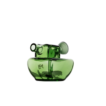 The MJ Arsenal Commander Blunt Bubbler is a modern, artistic green borosilicate glass piece with a unique wide base, short spout-like neck, and small circular handle on one side, displayed against a plain white background.