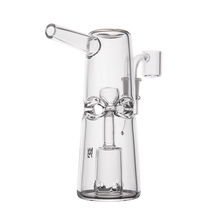 The MJ Arsenal Turret Mini Dab Rig features clear borosilicate glass, a cylindrical body, angled mouthpiece, and intricate internal percolator, delivering a sleek and portable dabbing experience.