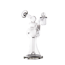 The MJ Arsenal Apollo Mini Dab Rig features clear borosilicate glass, a wide base, bent neck, top-mounted mouthpiece, circular chambers for flavor preservation, and an attached quartz banger—all shown against a plain white background.