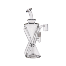 The MJ Arsenal Time Turner Mini Dab Rig is a clear borosilicate glass, hourglass-shaped piece with an angled mouthpiece and side attachment for a bowl or nail, perfect for dry herbs or concentrates. Its elegant curves give it a modern look.