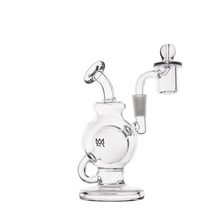 The MJ Arsenal Atlas Mini Dab Rig is a clear borosilicate glass dab rig with a round chamber, side handle, angled mouthpiece, and attached glass banger with carb cap, elegantly displayed on a white background.