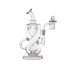 The MJ Arsenal Titan Mini Dab Rig is a clear borosilicate glass piece with multiple chambers, a curved mouthpiece, and a side arm holding a removable glass bowl with handle, shown against a white background.