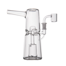 The MJ Arsenal Turret Mini Dab Rig is a clear borosilicate glass piece featuring a cylindrical body, angled left mouthpiece, and right quartz banger—compact and sleek, shown against a plain white background.