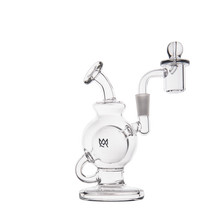 The MJ Arsenal Atlas Mini Dab Rig is a clear borosilicate glass water pipe with a round chamber, angled mouthpiece, side arm for a detachable bowl, sturdy base, minimalist design, and features a small crown logo on the front.