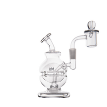 The MJ Arsenal Royale Mini Dab Rig is a clear borosilicate glass piece featuring a round chamber, angled mouthpiece, and an attached quartz banger with marble carb cap, displayed on a white background.