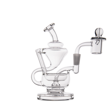 The MJ Arsenal Claude Mini Dab Rig, featuring clear glass, multiple chambers, curved tubes, and a detachable glass bowl, is displayed on a white background.