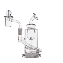 The MJ Arsenal Ursa Mini Dab Rig is a clear borosilicate glass water pipe with a cylindrical base, angled mouthpiece, and attached bowl and downstem, shown against a plain white background.