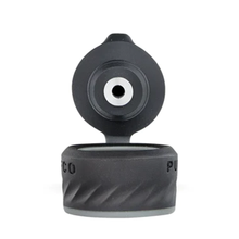 The Puffco Peak Pro Joystick Cap is a black plastic flip-top lid, open to show a central circular spout. It features a textured grip inspired by directional airflow joystick carb caps, with the word PUCO partially visible.