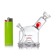 The MJ Arsenal x Tyson 2.0 Punch-Out, a small clear borosilicate glass cone bubbler with branded logos, sits beside a lime green lighter on a white background.