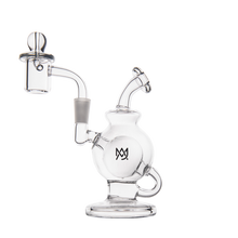 The MJ Arsenal Atlas Mini Dab Rig is a compact clear borosilicate glass rig with a round base, curved mouthpiece, side handle, removable dome and nail, and a black overlapping letter logo on the main chamber.
