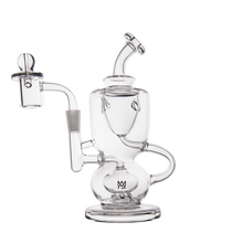 The MJ Arsenal Titan Mini Dab Rig is a clear borosilicate glass piece with an intricate, curvy design, rounded base, side handle, angled mouthpiece, and attached quartz banger. The logo appears near the base. Shown on a plain white background.