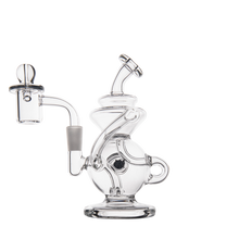 The MJ Arsenal Mini Jig Mini Dab Rig features clear glass with a unique curvy design, round base, angled mouthpiece, attached banger and carb cap, plus a built-in storage jar. Shown on a plain white background.