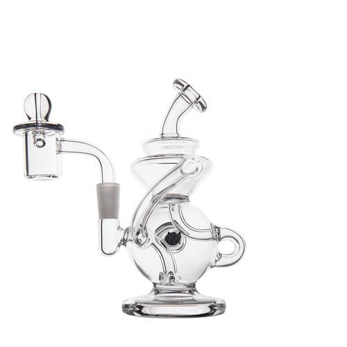 The MJ Arsenal Mini Jig Mini Dab Rig features clear glass with a unique curvy design, round base, angled mouthpiece, attached banger and carb cap, plus a built-in storage jar. Shown on a plain white background.