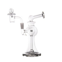 The MJ Arsenal Apollo Mini Dab Rig, made of clear borosilicate glass with a round base, angled mouthpiece, and side-mounted bowl attachment, stands upright against a plain white background for optimal flavor preservation.