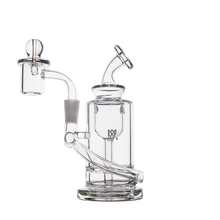 The MJ Arsenal Ursa Mini Dab Rig is a clear borosilicate glass water pipe with a cylindrical base, angled mouthpiece, curved neck, side chamber, domed cap, attachment joint, and modern minimalistic design.