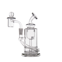 The MJ Arsenal Ursa Mini Dab Rig features clear borosilicate glass with a cylindrical chamber, angled mouthpiece, domed quartz banger, and stable round base, all displayed on a plain white background.