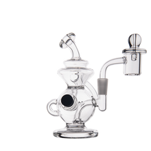 The MJ Arsenal Mini Jig Mini Dab Rig features clear glass, a round base, curved neck, cylindrical attachments, built-in storage jar, and recycler design for smooth smoking or vaporizing; shown on a plain white background.