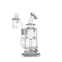 The MJ Arsenal Ursa Mini Dab Rig, made of clear borosilicate glass with a cylindrical chamber, angled mouthpiece, fixed downstem, and quartz banger attachment, sits on a white background.