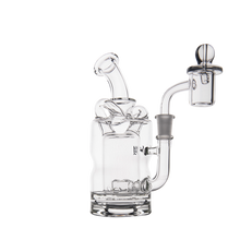 The MJ Arsenal Turbine Mini Dab Rig is a clear borosilicate glass piece with a curved mouthpiece, cylindrical chamber, side arm, quartz banger, and glass carb cap, shown on a white background.