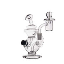 The MJ Arsenal Mini Jig Mini Dab Rig is a clear glass piece with a rounded base, side mouthpiece, removable glass bowl attachment, and built-in storage jar, shown against a plain white background.
