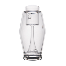 The MJ Arsenal Proxy Bubbler is a clear borosilicate glass carafe with a transparent stemmed glass stored upside down inside it—an elegant piece that serves as a unique dabbing accessory, displayed on a plain white background.