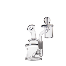 The MJ Arsenal Jammer Mini Dab Rig, crafted from clear borosilicate glass with multiple chambers and a curved stem, features a dome-shaped attachment. Its compact design ensures smooth sessions and easy portability, shown against a plain white background.
