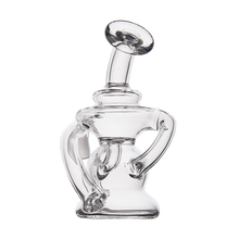 The MJ Arsenal Hydra Vape Edition is a clear glass mini dab rig with an abstract, sculptural design, featuring two curved arms and a tilted mouthpiece, shown against a white background.