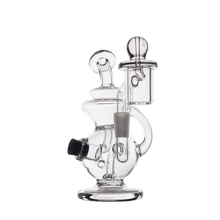 The MJ Arsenal Mini Jig Mini Dab Rig features clear glass with intricate curves, a side mouthpiece, bowl attachment, cylindrical chamber with top handle, and built-in storage jar—all set against a plain white background.