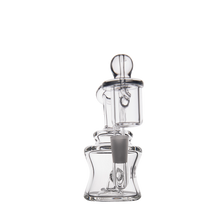 The MJ Arsenal Jammer Mini Dab Rig, crafted from clear borosilicate glass with an angular base, cylindrical chamber, and attached downstem, is shown against a plain white background.