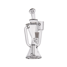 The MJ Arsenal Time Turner Mini Dab Rig is a clear borosilicate glass rig with an intricate geometric design, multiple chambers, curved tubing, and a funnel-shaped base, displayed on a plain white background.