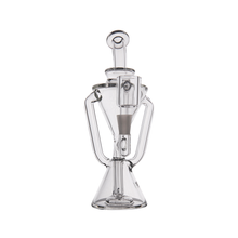 The MJ Arsenal Time Turner Mini Dab Rig is a clear borosilicate glass piece with a geometric design, hourglass-shaped base, dual side handles, and a central vertical chamber.