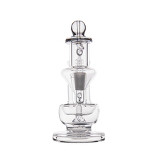 The MJ Arsenal Claude Mini Dab Rig is a clear glass recycler-style apparatus with a cylindrical base, multiple chambers, and a rounded top, displayed against a plain white background.
