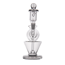 The MJ Arsenal Gemini Mini Dab Rig features a clear borosilicate glass build with a conical base, spherical center, and cylindrical top, connected vertically. Its sleek lines evoke the look of a classic portable dab rig.