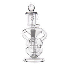 The MJ Arsenal Infinity Mini Dab Rig, made of clear borosilicate glass with a round base, curved handles, and intricate internal pathways, stands out against a plain white background.
