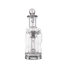The MJ Arsenal Turbine Mini Dab Rig, crafted from clear borosilicate glass with a glass stopper and intricate design details, is showcased against a plain white background.