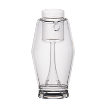 The MJ Arsenal Proxy Bubbler, made of clear borosilicate glass with a wide base, narrow neck, and central stem suspending an inner chamber, is shown elegantly against a white background.