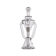 The MJ Arsenal Time Turner Mini Dab Rig is a clear borosilicate glass rig with a geometric design, featuring a conical base, angled side arms, and a cylindrical mouthpiece.