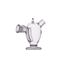 The MJ Arsenal Dubbler Original Double Bubbler, made of clear borosilicate glass with a rounded body, left-side wide spout, small top mouthpiece, and flat circular base, is shown on a white background.