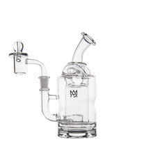 The MJ Arsenal Turbine Mini Dab Rig is a clear borosilicate glass water pipe with a round base, angled mouthpiece, attached bowl, MJ logo on the front, and detailed glasswork inspired by its signature design.